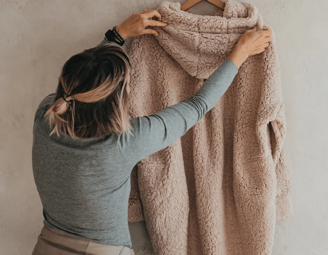 PatentDuo organikus pamut és textil ruhákat viselő nő Sherpa pulóvert tart